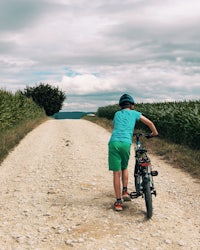 a boy riding a bike down a dirt road