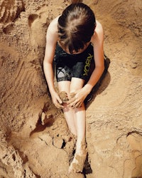 a boy sitting in the sand with his hands in the sand