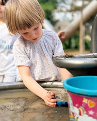 a little girl playing in the mud at a playground