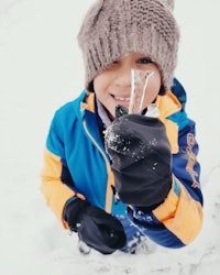 a young boy holding an ice cube in the snow